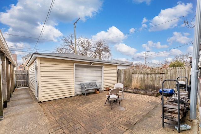 view of patio featuring a garage, a fenced backyard, and an outdoor structure