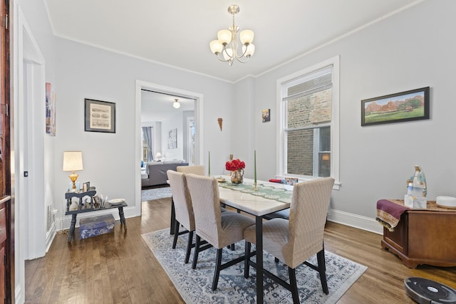 dining space featuring baseboards, ornamental molding, wood finished floors, and an inviting chandelier