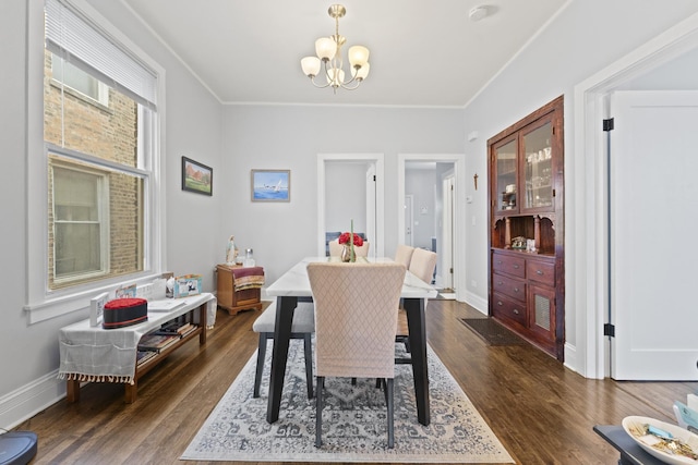 dining room with a chandelier, dark wood-type flooring, ornamental molding, and baseboards