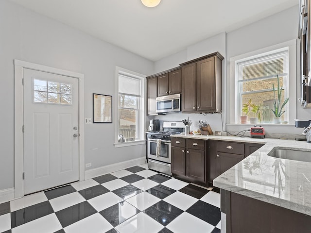 kitchen featuring appliances with stainless steel finishes, a sink, dark brown cabinetry, and tile patterned floors