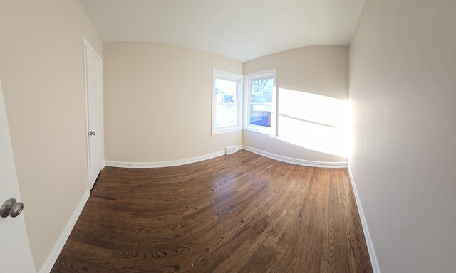 unfurnished room featuring dark wood-style floors, visible vents, and baseboards