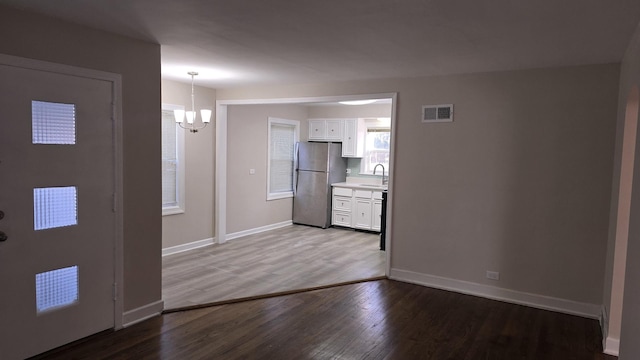 foyer with visible vents, baseboards, an inviting chandelier, and wood finished floors