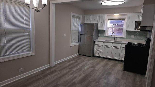 kitchen with black range with gas cooktop, white cabinetry, freestanding refrigerator, and a sink