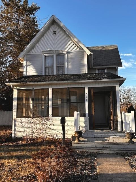 view of front of property featuring a sunroom, covered porch, and fence