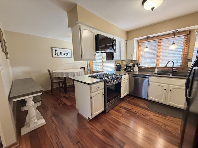 kitchen featuring stainless steel appliances, a sink, white cabinetry, dark wood-style floors, and dark countertops