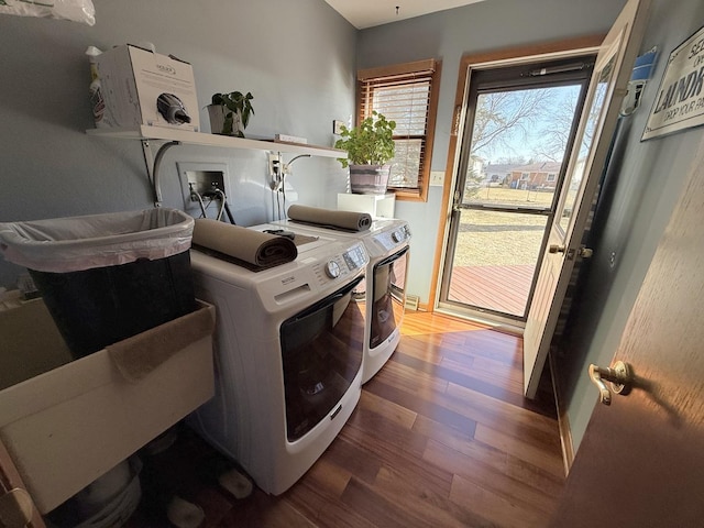 clothes washing area featuring laundry area, wood finished floors, and washing machine and clothes dryer