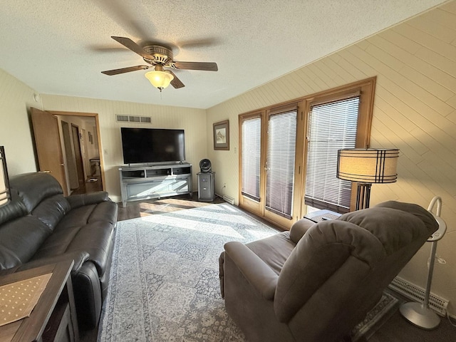 living area featuring a ceiling fan, visible vents, and a textured ceiling