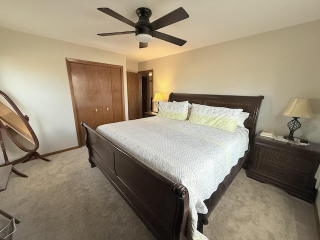 bedroom with light carpet, ceiling fan, a closet, and baseboards