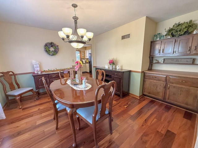 dining room featuring an inviting chandelier, light wood-style flooring, visible vents, and baseboards