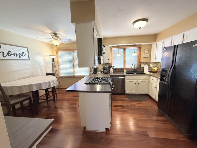 kitchen with dark countertops, stainless steel appliances, a peninsula, and white cabinetry