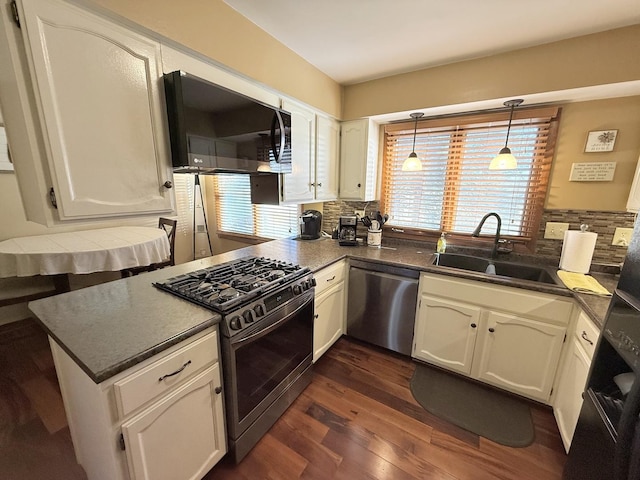 kitchen featuring a sink, white cabinets, appliances with stainless steel finishes, decorative backsplash, and dark wood-style floors