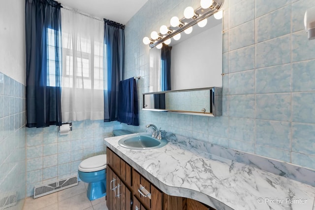 bathroom featuring tile walls, visible vents, toilet, vanity, and tile patterned flooring