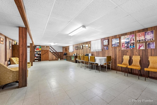 interior space featuring a paneled ceiling, wood walls, and stairway