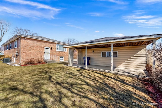 back of house with central AC unit, a yard, brick siding, and a patio area