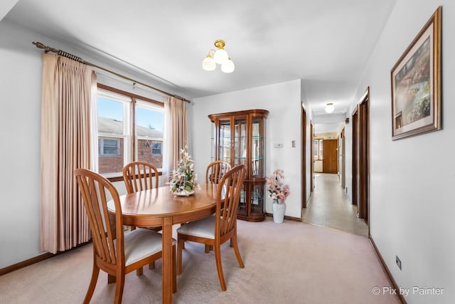 dining area featuring light carpet and baseboards