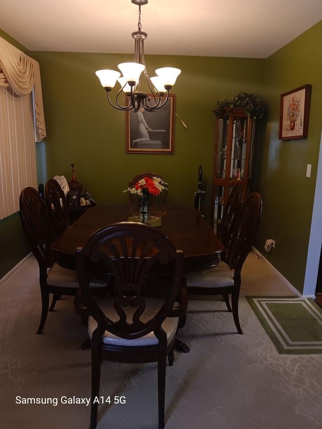 carpeted dining room with baseboards and a chandelier