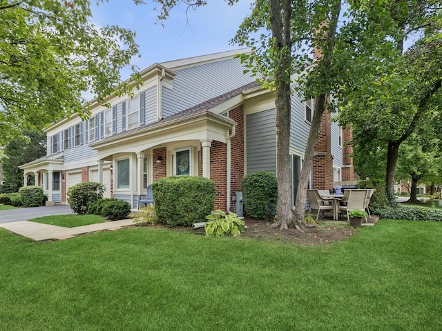 view of front of home with brick siding, driveway, a front lawn, and a garage