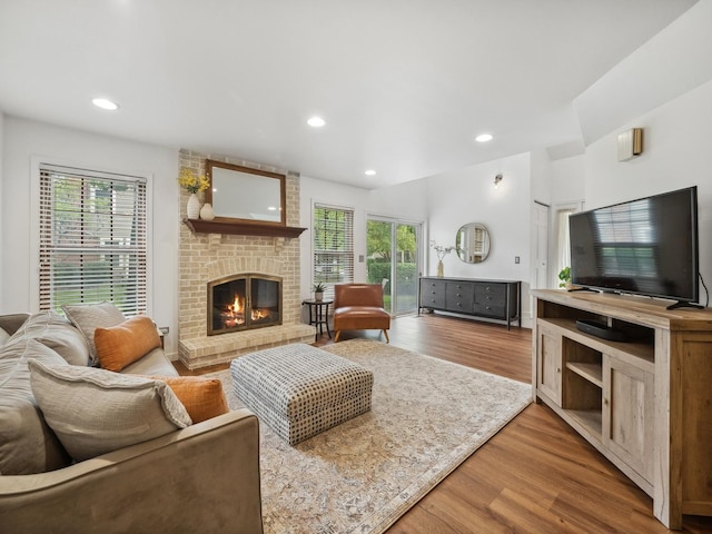 living room featuring recessed lighting, a brick fireplace, and light wood-style floors