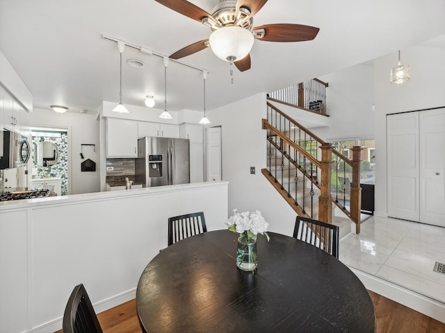 dining area featuring a ceiling fan and stairs