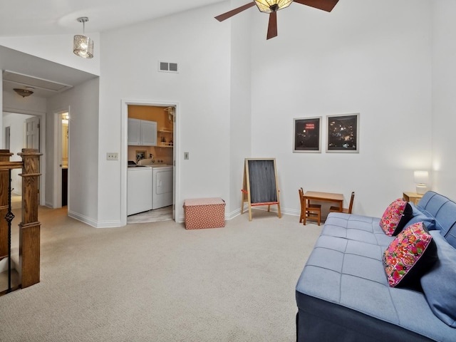 living room featuring washer and dryer, light colored carpet, visible vents, and high vaulted ceiling