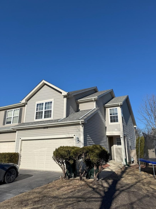 view of front of property featuring a trampoline, driveway, and an attached garage