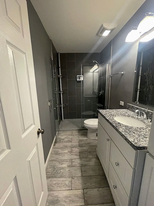 bathroom featuring toilet, visible vents, a shower stall, and vanity