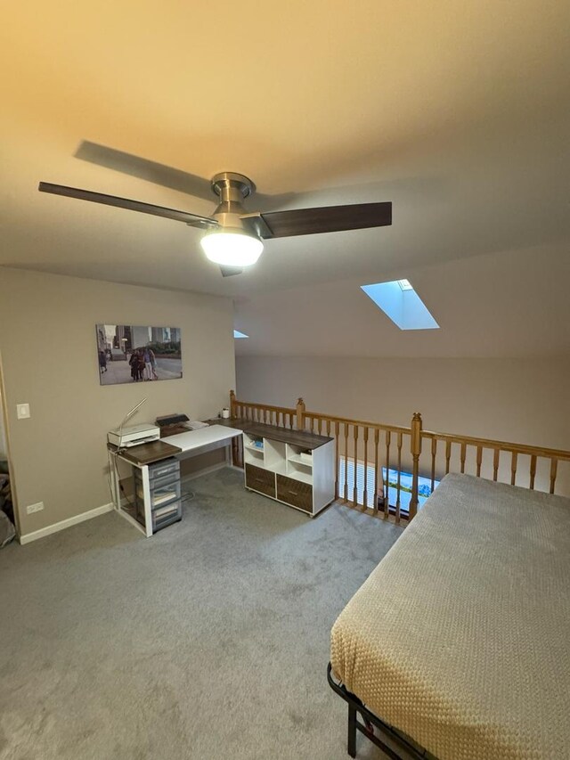 bedroom with carpet floors, vaulted ceiling with skylight, baseboards, and ceiling fan