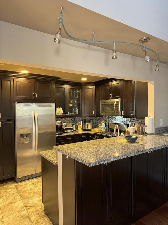 kitchen with a peninsula, glass insert cabinets, stainless steel appliances, and backsplash