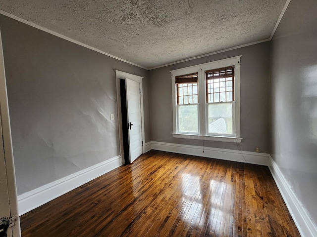 unfurnished room featuring dark wood-type flooring, ornamental molding, a textured ceiling, and baseboards