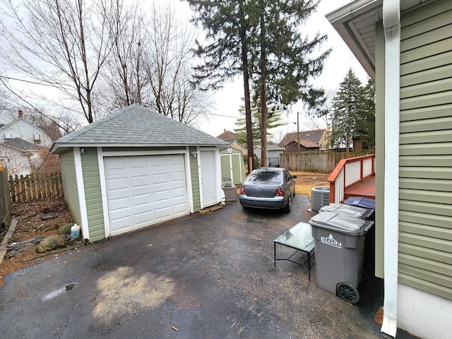 detached garage featuring fence and cooling unit