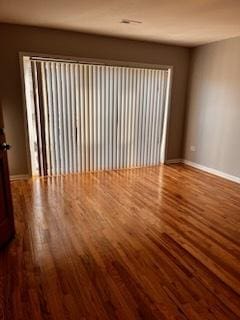 spare room featuring baseboards and wood finished floors