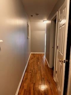 corridor with baseboards and wood finished floors