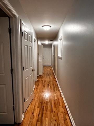 hallway featuring light wood finished floors and baseboards