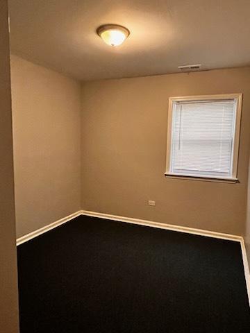 empty room with carpet, visible vents, and baseboards