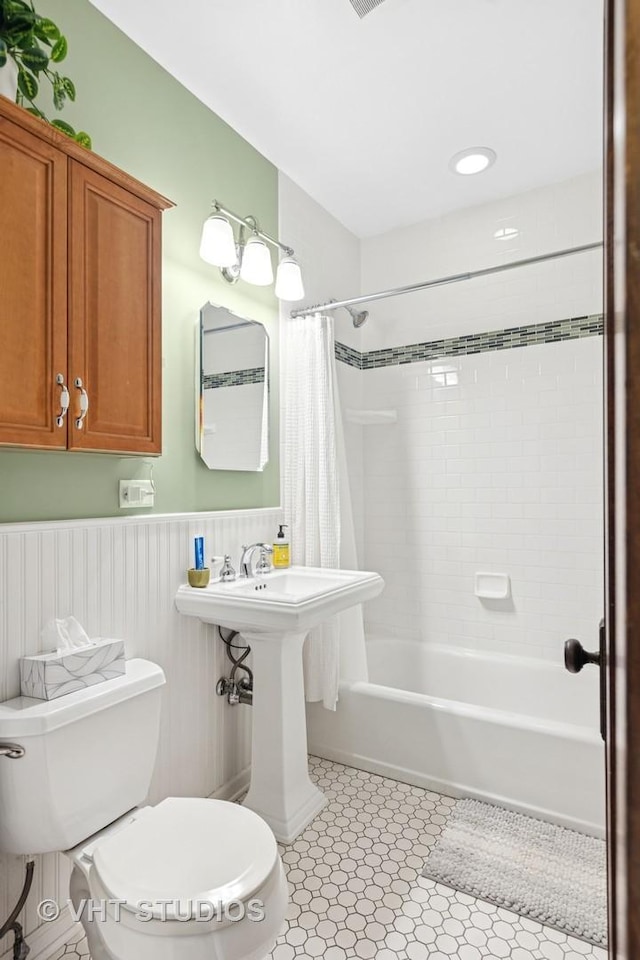 full bath featuring a sink, wainscoting, toilet, and shower / bath combo