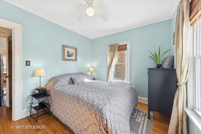 bedroom with baseboards, wood finished floors, a ceiling fan, and ornamental molding