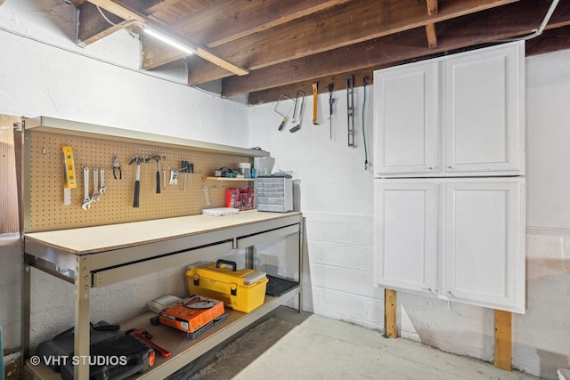 unfinished basement featuring a workshop area and concrete block wall