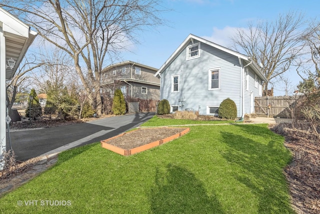 view of home's exterior with aphalt driveway, a yard, and fence