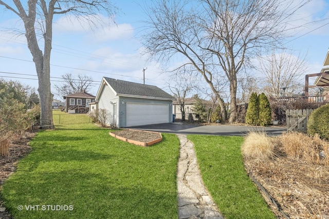 view of yard with a garage, an outbuilding, driveway, and fence