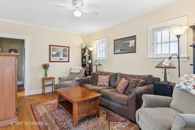 living room with plenty of natural light, light wood-style floors, a ceiling fan, and ornamental molding