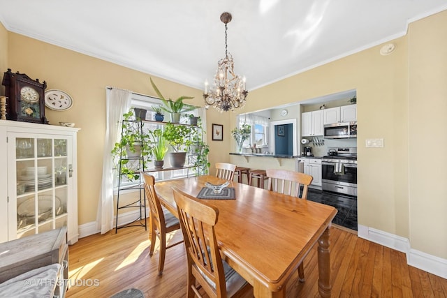 dining space featuring a chandelier, light wood finished floors, a wealth of natural light, and ornamental molding