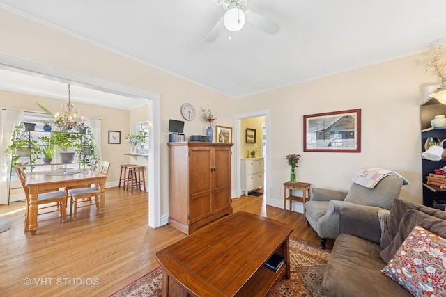 living area featuring baseboards, ceiling fan with notable chandelier, and light wood finished floors