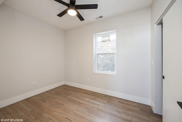 empty room featuring light wood-style floors, visible vents, baseboards, and a ceiling fan