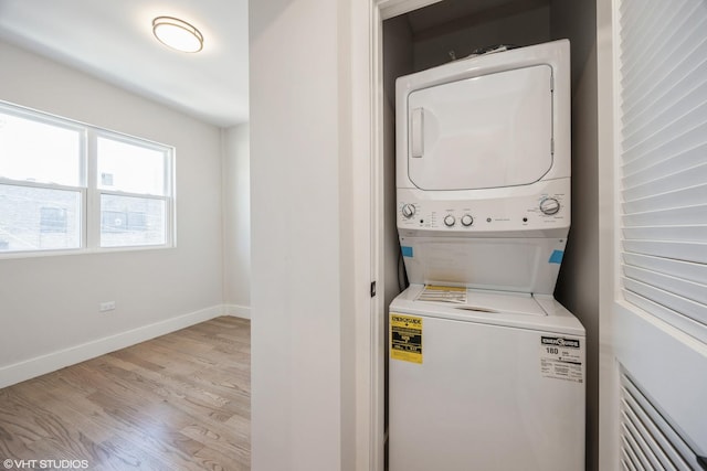 washroom with baseboards, laundry area, wood finished floors, and stacked washer / drying machine