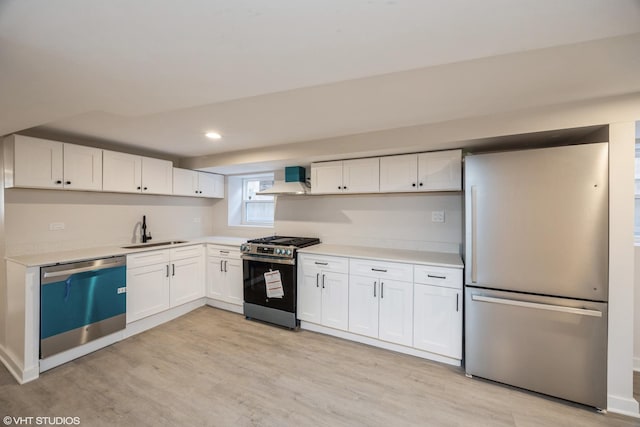 kitchen featuring white cabinets, light wood-style flooring, stainless steel appliances, and a sink