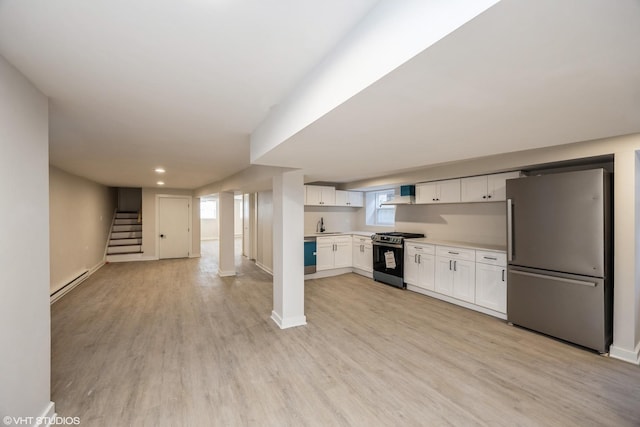 kitchen with light wood finished floors, a baseboard radiator, appliances with stainless steel finishes, and white cabinets