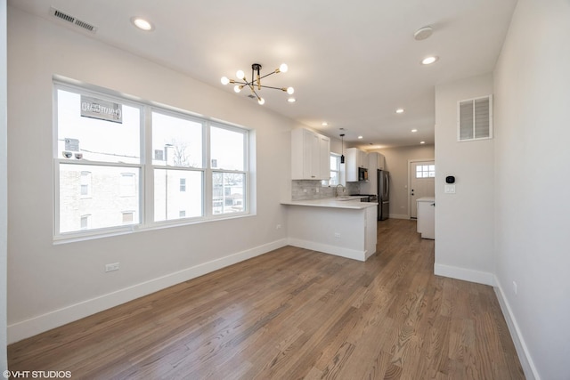 kitchen with tasteful backsplash, freestanding refrigerator, light countertops, and visible vents