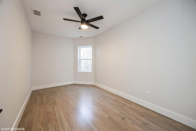 spare room featuring baseboards, visible vents, ceiling fan, and wood finished floors