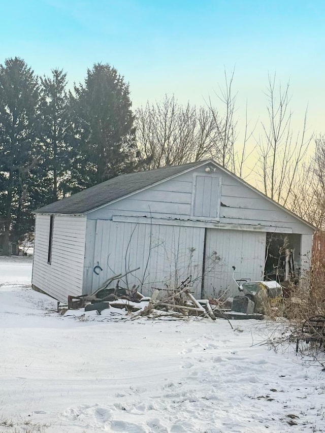 snow covered structure with an outbuilding