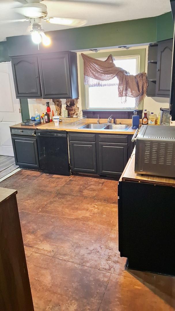 kitchen with black dishwasher, light countertops, a sink, and a ceiling fan